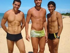 Big muscled dudes are wearing tight trunks at the beach